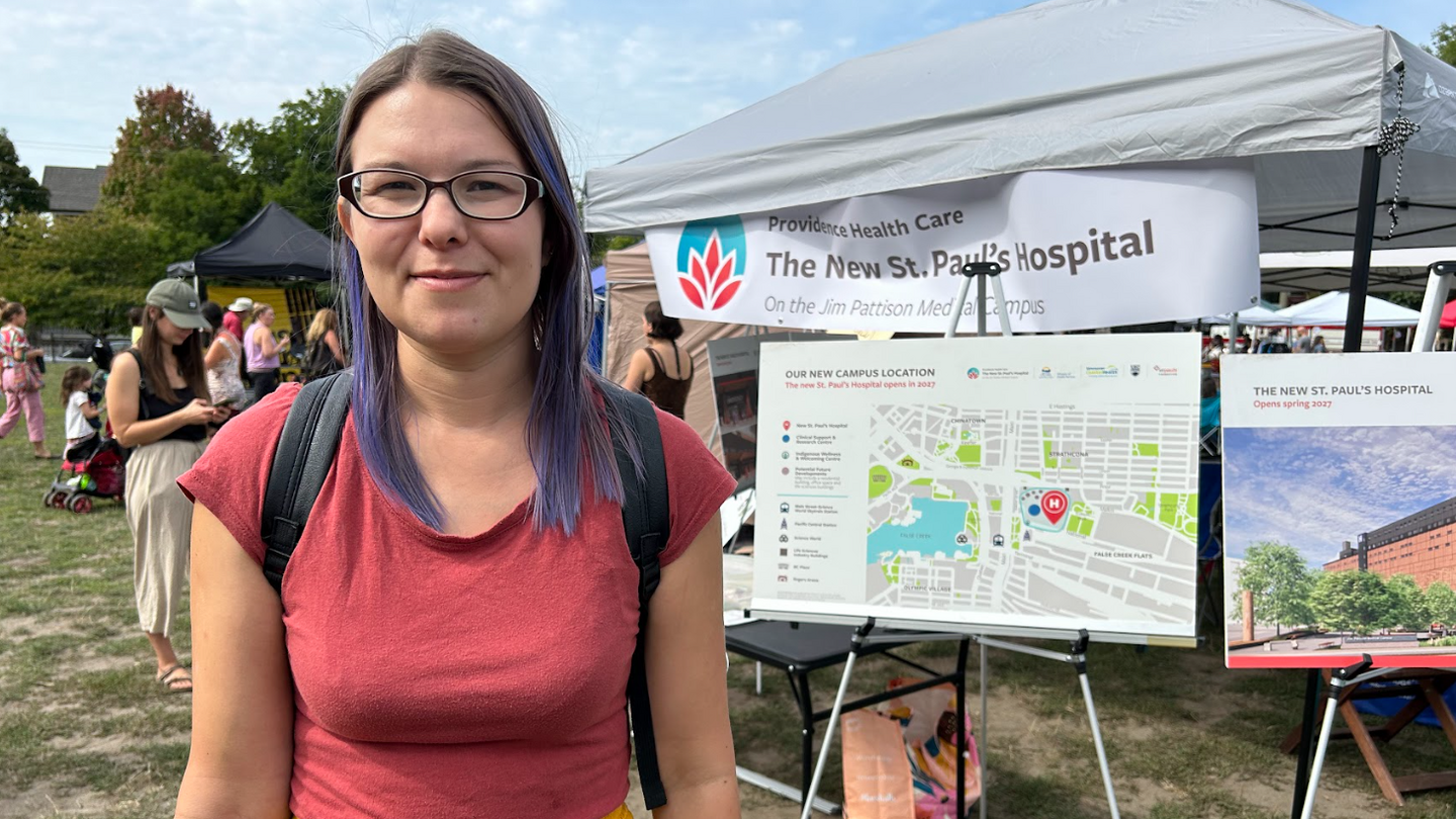 A woman stands in front of a signboard